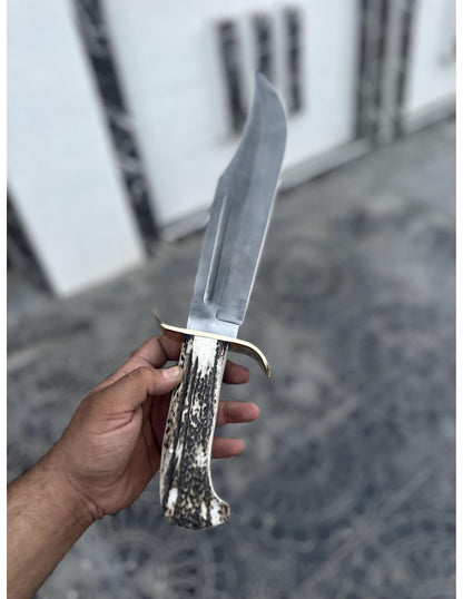 Detailed stag handle with brass guard on handmade full tang Bowie knife.