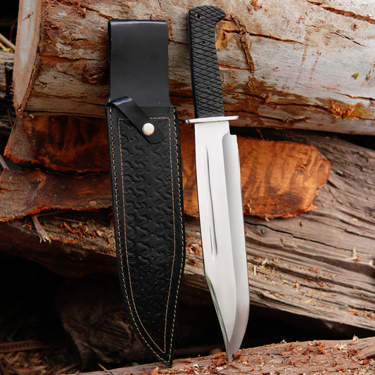 Handmade bowie knife with black textured handle placed on natural wood background showing full tang construction and clean blade finish suitable for outdoor camping bushcraft and collectors looking for durable handmade carbon steel knife with leather sheath for safe carry and long term use.