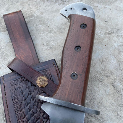 Close-up of handmade Bowie knife with full tang design and solid wood handle, showing detailed craftsmanship and brass hardware.