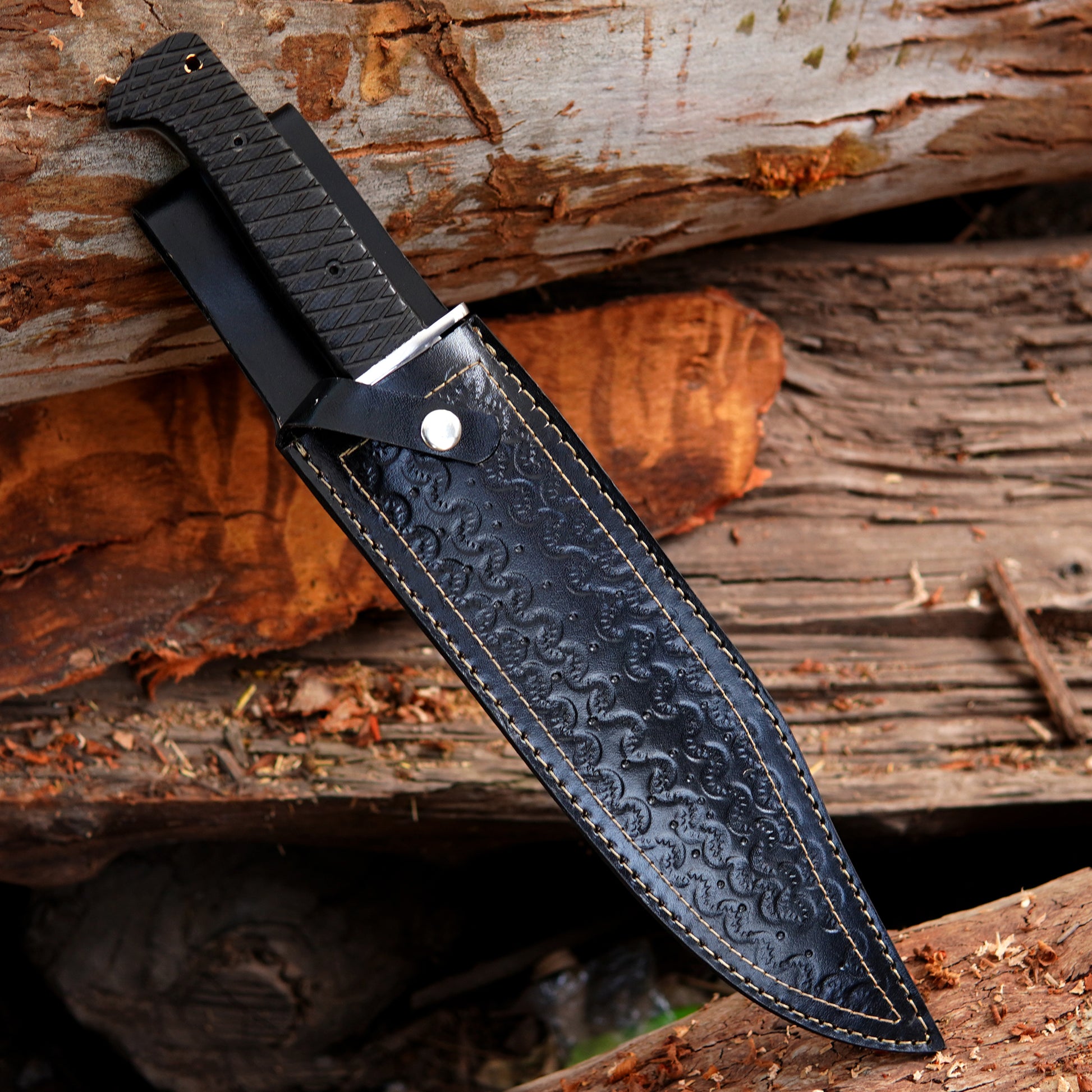Full tang bowie knife displayed with leather sheath in outdoor setting showing strong blade profile and secure handle grip ideal for camping survival bushcraft and outdoor enthusiasts who prefer reliable handmade knives with classic design and durable materials.