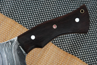 This full tang meat chopper is forged from Damascus steel and finished with a strong wenge wood handle. Handmade for strength and comfort, it works perfectly for heavy chopping tasks in the kitchen or outdoors. Free engraving option included.