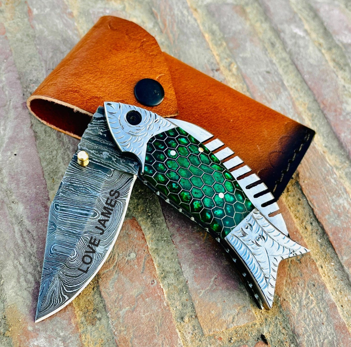 Handmade Damascus steel knife close up showing beautiful layered steel pattern and detailed craftsmanship.