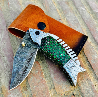 Handmade Damascus steel knife close up showing beautiful layered steel pattern and detailed craftsmanship.