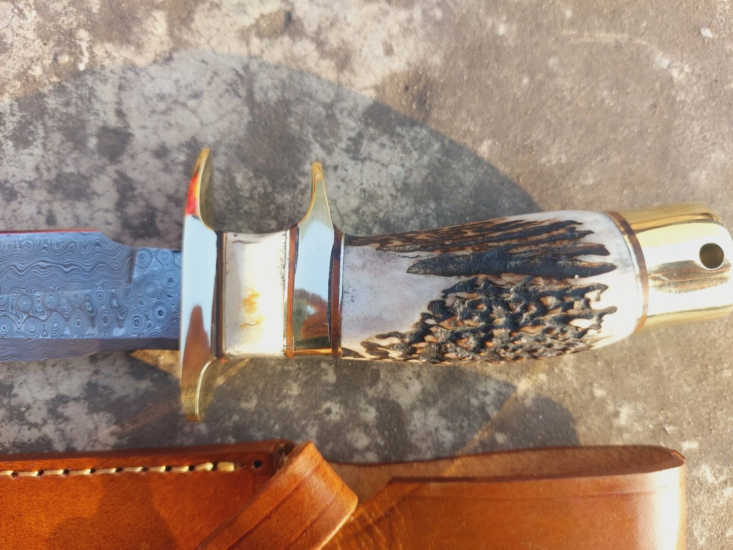 Damascus steel fixed blade knife with natural handle, brass guard, and hand stitched leather sheath. This handcrafted knife is designed for outdoor use, hunting, and camping, offering durability and a sharp edge with the beauty of damascus patterns. Perfect for those who value artistry, strength, and practicality in a handmade hunting knife.