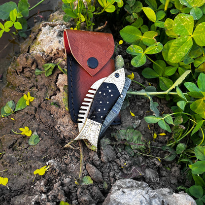 Close view of Damascus steel fish pocket knife showing detailed blade pattern and black scale handle texture.