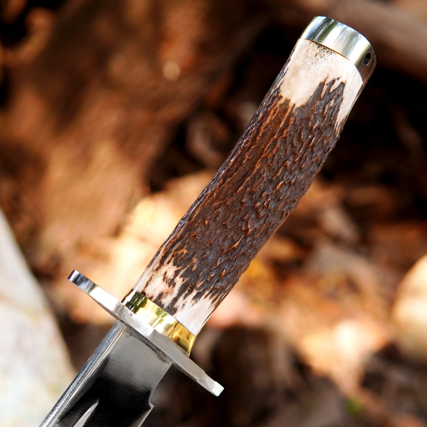 Handmade bowie style knife shown in an outdoor setting highlighting balance and craftsmanship.