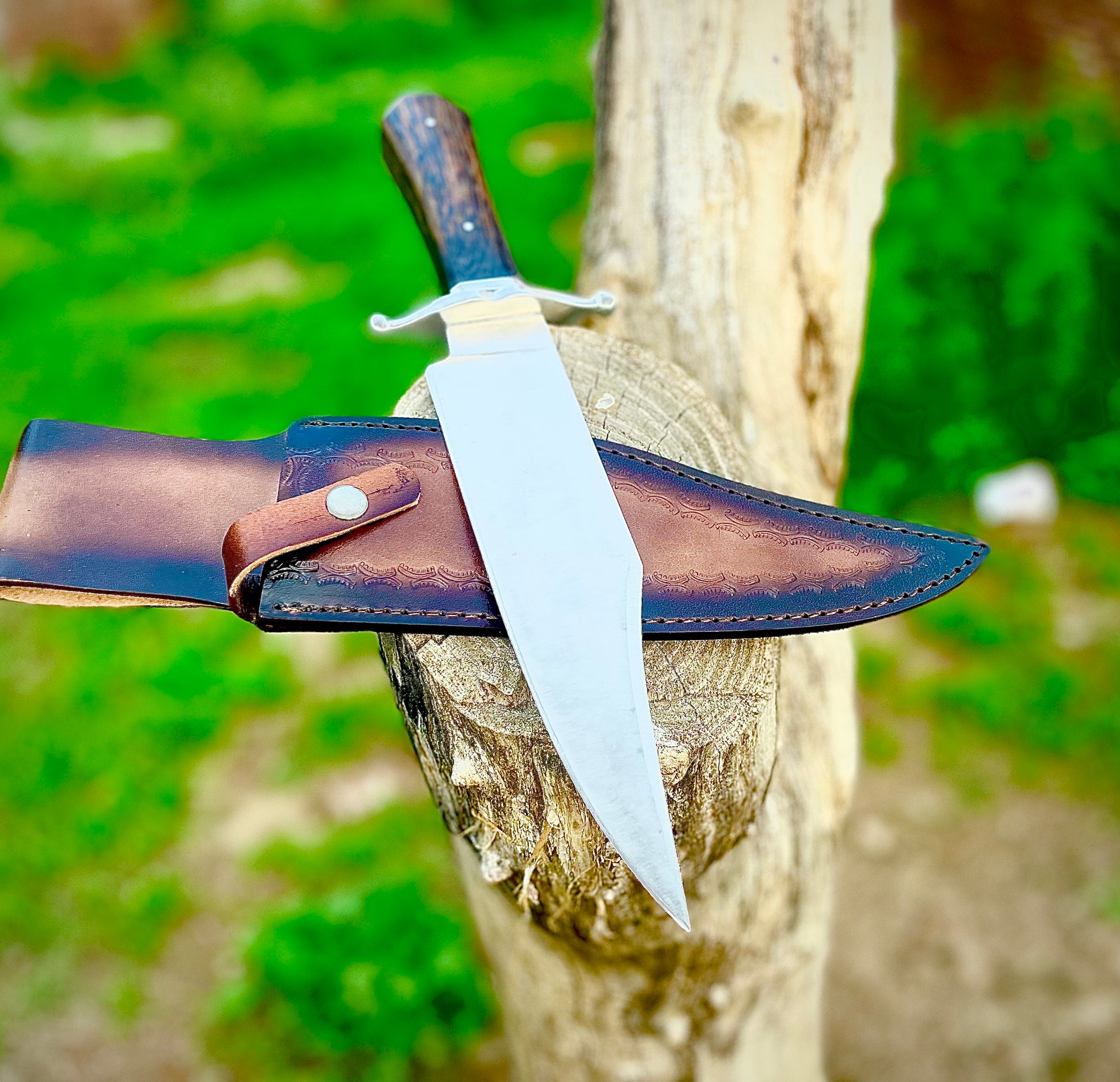 Hunting Bowie knife made from high-quality 1095 carbon steel, fitted with a dark wenge wood handle and protective leather sheath for outdoor use.