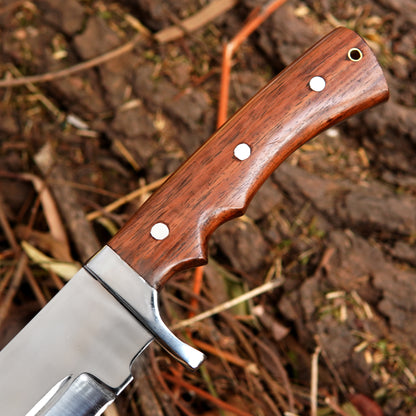 Handmade bowie knife placed in outdoor setting with natural background demonstrating realistic use environment and highlighting balanced design for camping and survival tasks.