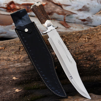 Handmade carbon steel Bowie knife with polished clip point blade displayed vertically on rustic wooden background.