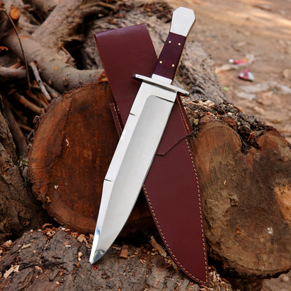 Handmade bowie style knife with polished steel blade, wooden handle, and premium leather sheath displayed on wood.