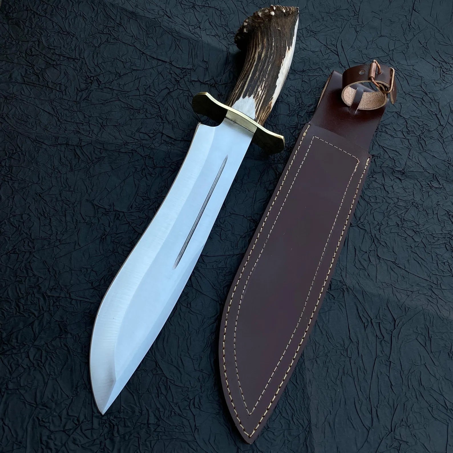 Handmade Bowie knife with carbon steel blade, crown stag handle, and leather sheath, designed for outdoor hunting and collecting.