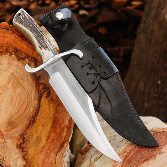 Handmade bowie style knife with polished steel blade, natural material handle, and black leather sheath.