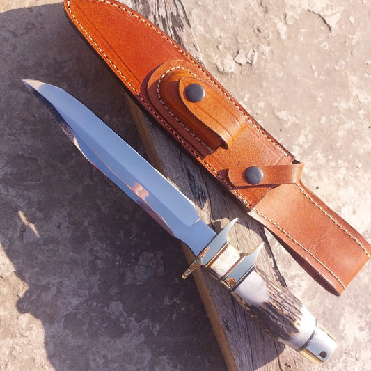 Handmade hunting knife crafted with carbon steel mirror shine blade and stag antler handle. Fitted with brass guard and pommel for strength and balance, this knife is supplied with a genuine leather sheath. Built for hunters, outdoor use, and collectors, the polished blade and rugged handle give it both beauty and durability.