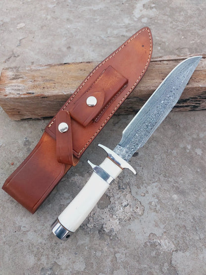 Damascus steel hunting knife with bone handle and brass fittings, offering a secure grip and classic look. Blade patterns are forged by hand, and sheath is stitched from genuine leather. Designed for hunters and collectors.