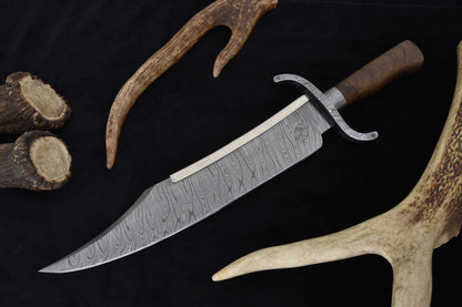 Handmade Damascus Texas Bowie knife featuring a large 14-inch blade with layered Damascus steel pattern, walnut wood handle, and forged guard. Comes with a custom wooden scabbard wrapped in leather. Perfect for collectors, hunters, and outdoor enthusiasts looking for a powerful handmade knife.