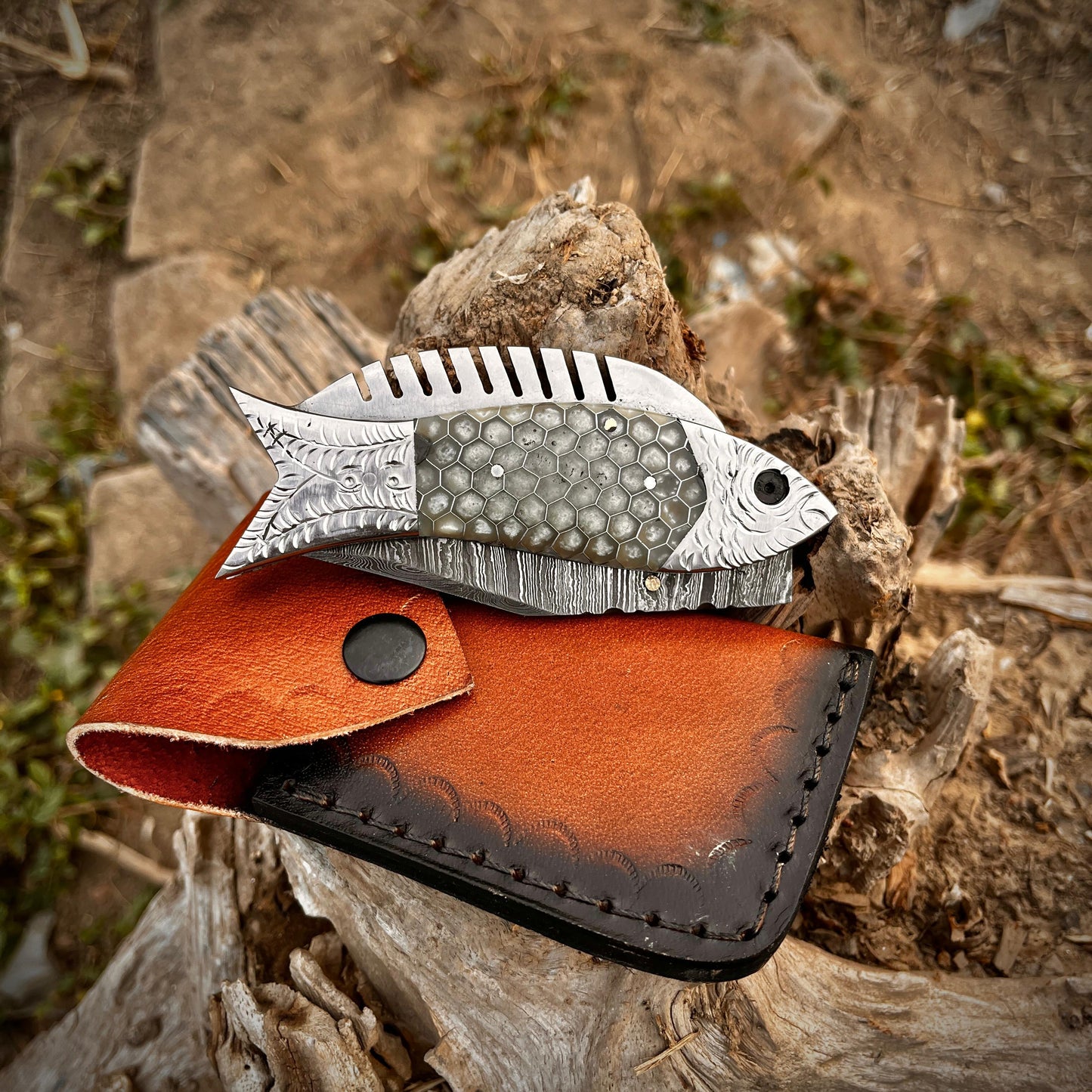 Artisan Damascus fish pocket knife with honeycomb handle design shown close up highlighting the layered Damascus steel blade pattern.