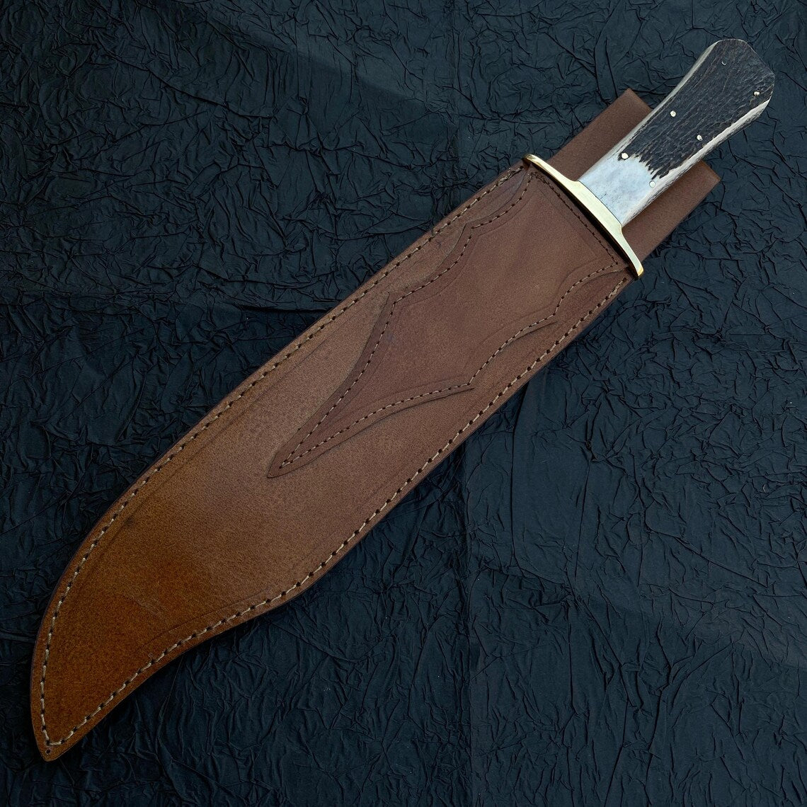 Brass guard detail of handmade Bowie knife with stag grip.