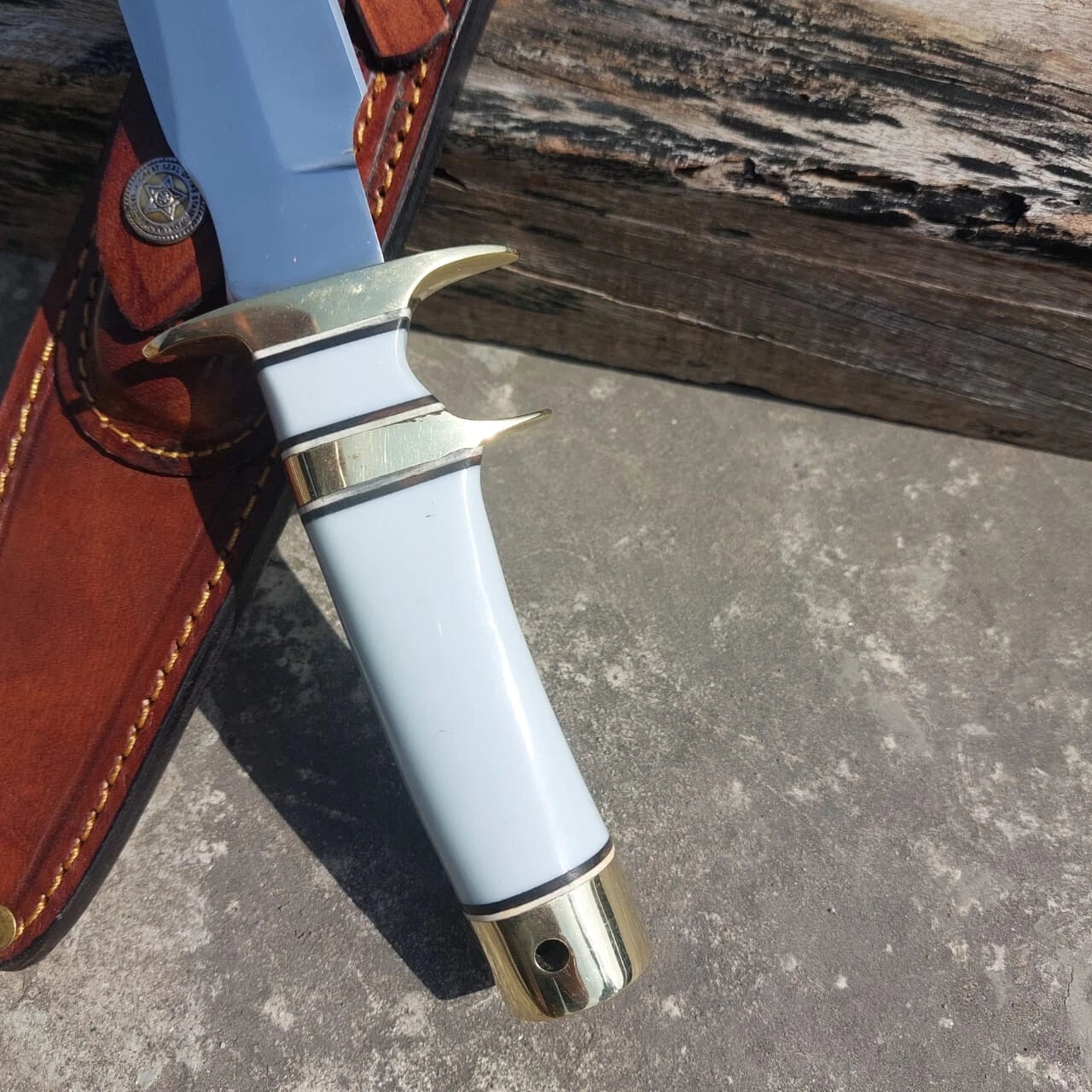 Polished hunting knife with white handle grip and leather sheath. The mirror finish blade ensures sharpness and durability, while the sheath offers safe carrying during outdoor use.