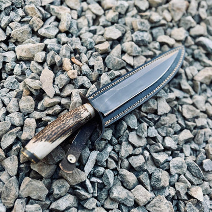 Full tang handmade hunting Bowie knife forged from 5160 spring steel, with ergonomic stag handle and rugged leather sheath for durability and timeless appeal.