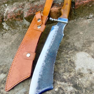 Hunting machete photographed on rock background emphasizing the forged finish.
