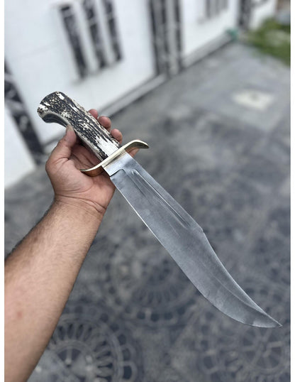 Handmade Bowie knife with brown leather sheath, carbon steel blade, and stag handle.