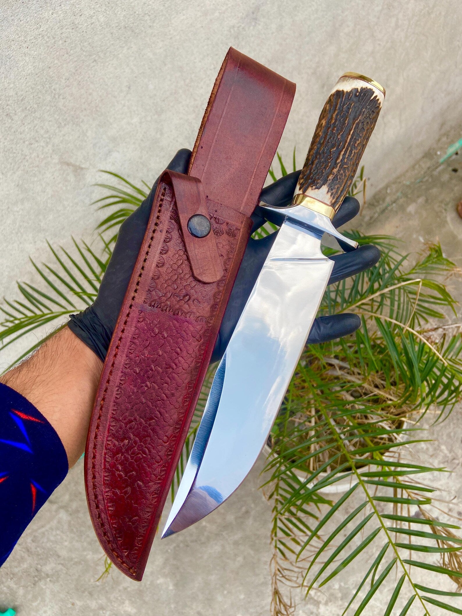 Close-up of handmade Bowie knife handle crafted from natural material with detailed brass guard and polished finish.