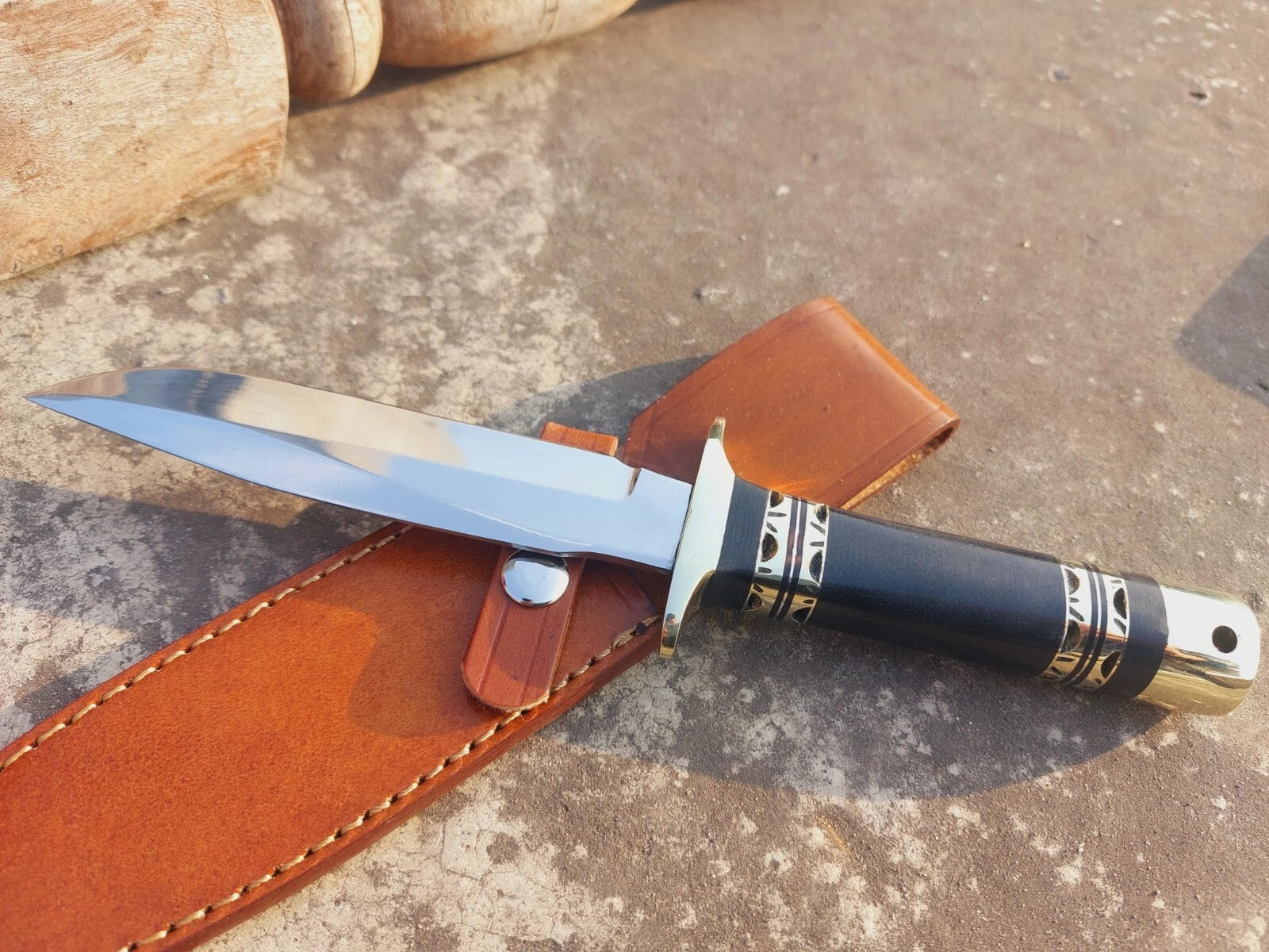 Outdoor hunting knife crafted with a polished steel blade, micarta handle for strong grip, and brass fittings for balance. Includes hand-stitched leather sheath, offering functionality and traditional handmade craftsmanship.