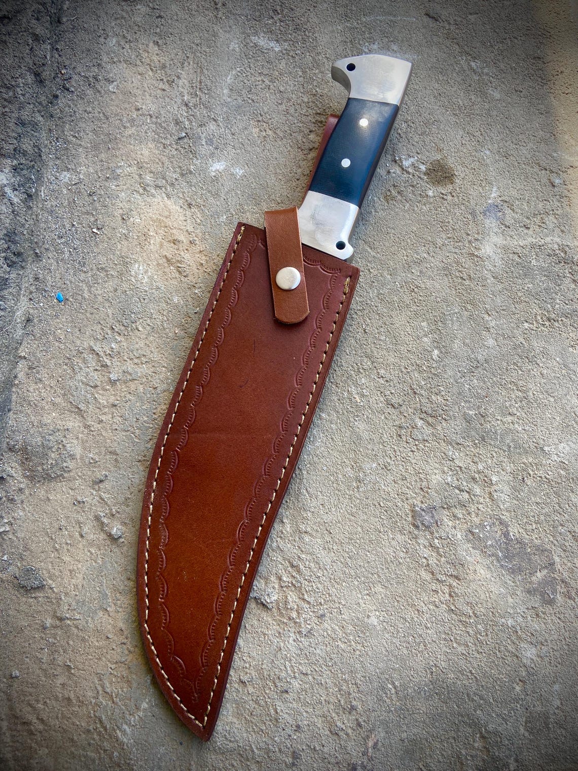 Handstitched brown leather sheath designed for a full tang bowie knife with belt loop.