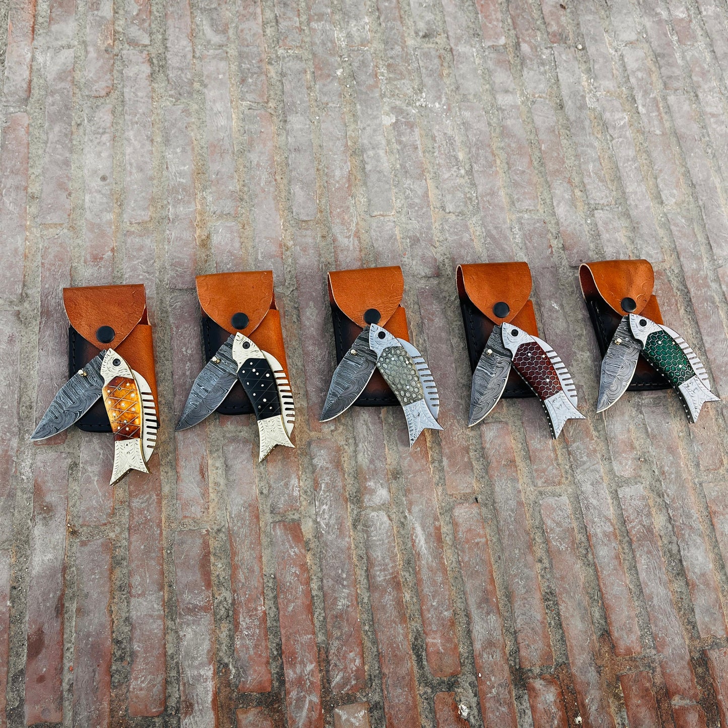 Close view of fish shaped Damascus pocket knife handle with honeycomb pattern and engraved metal details.