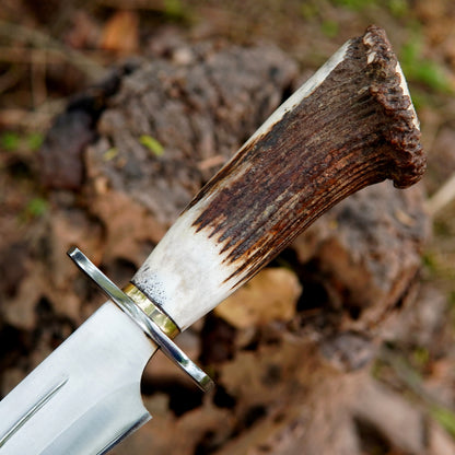 Knife inside black leather sheath resting on tree stump in forest background, perfect carry solution for belt attachment and quick access during hiking hunting and camping trips