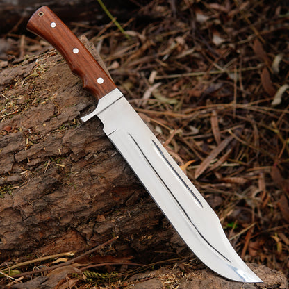 Outdoor bowie knife displayed with leather sheath on wooden surface highlighting handmade craftsmanship, strong blade structure and practical design for camping and outdoor use.