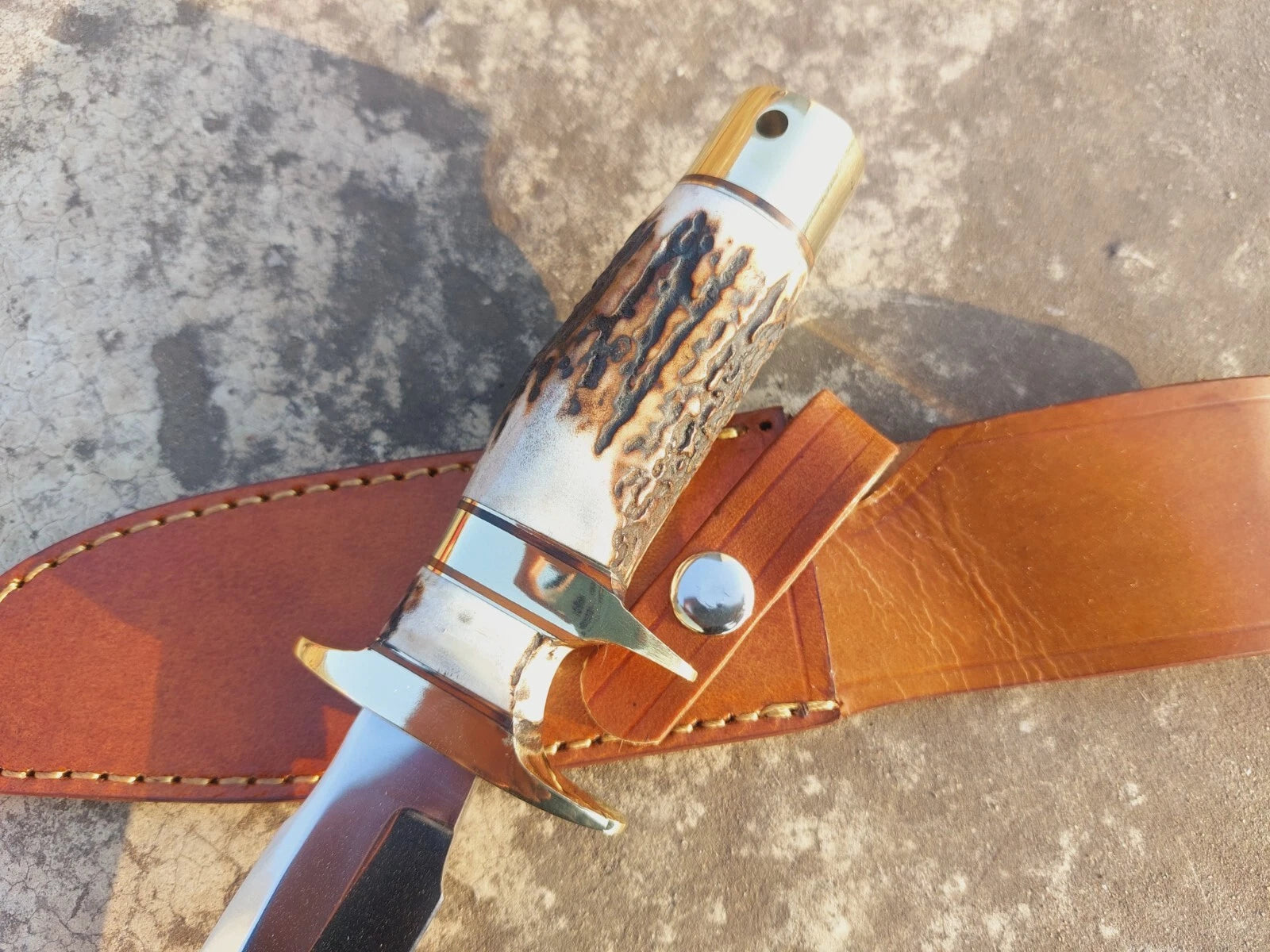 Mirror-polished carbon steel hunting knife featuring a natural handle, brass guard, and butt cap for strength and balance. The blade is sharp and resilient, complemented by a leather sheath to keep it safe for everyday carry, hunting, and outdoor adventures.