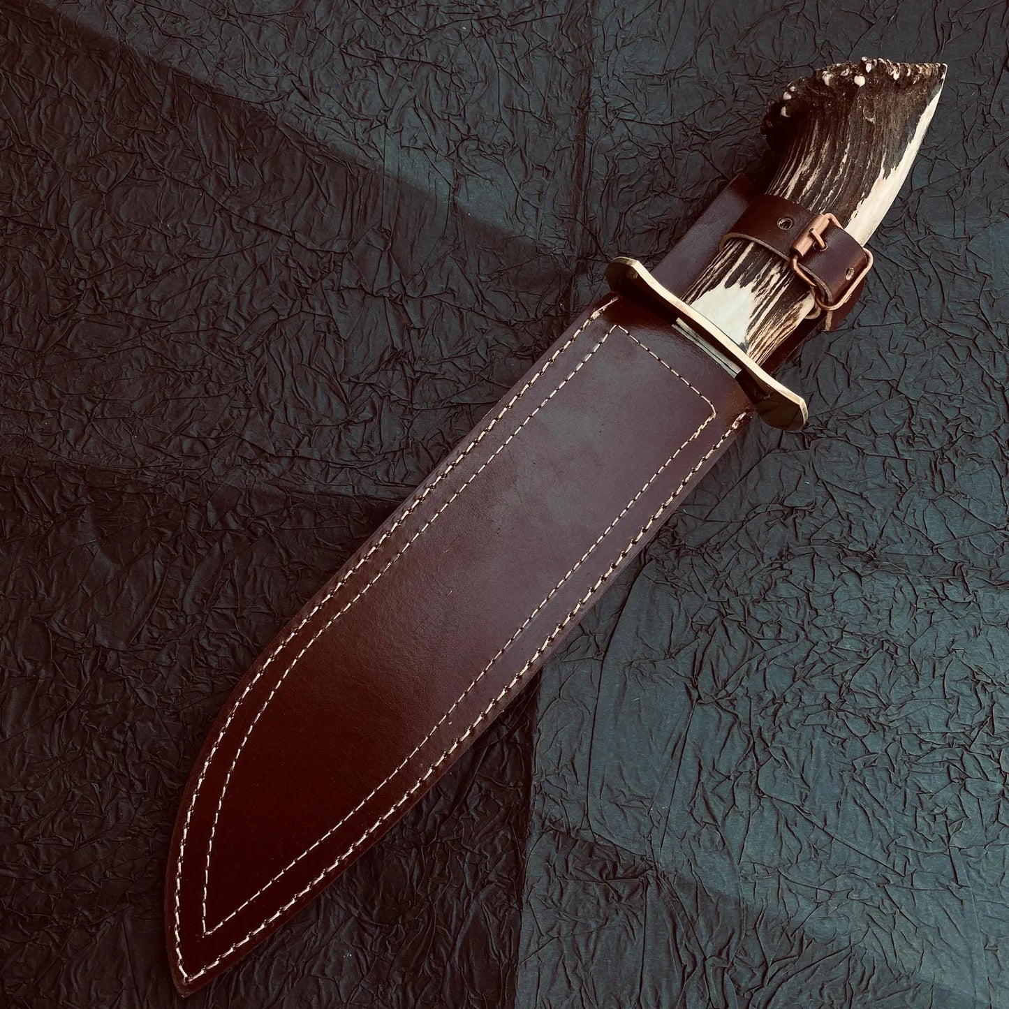 Large Bowie knife ideal for outdoor survival, showcasing hand-forged carbon steel blade and ergonomic stag grip.