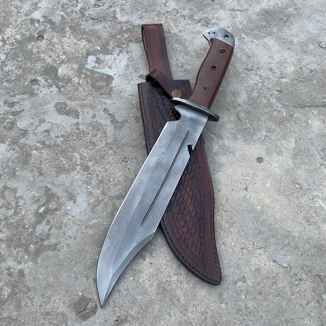 Custom handmade Bowie knife with 5160 spring steel blade featuring a fuller groove and a premium brown leather sheath for outdoor use.