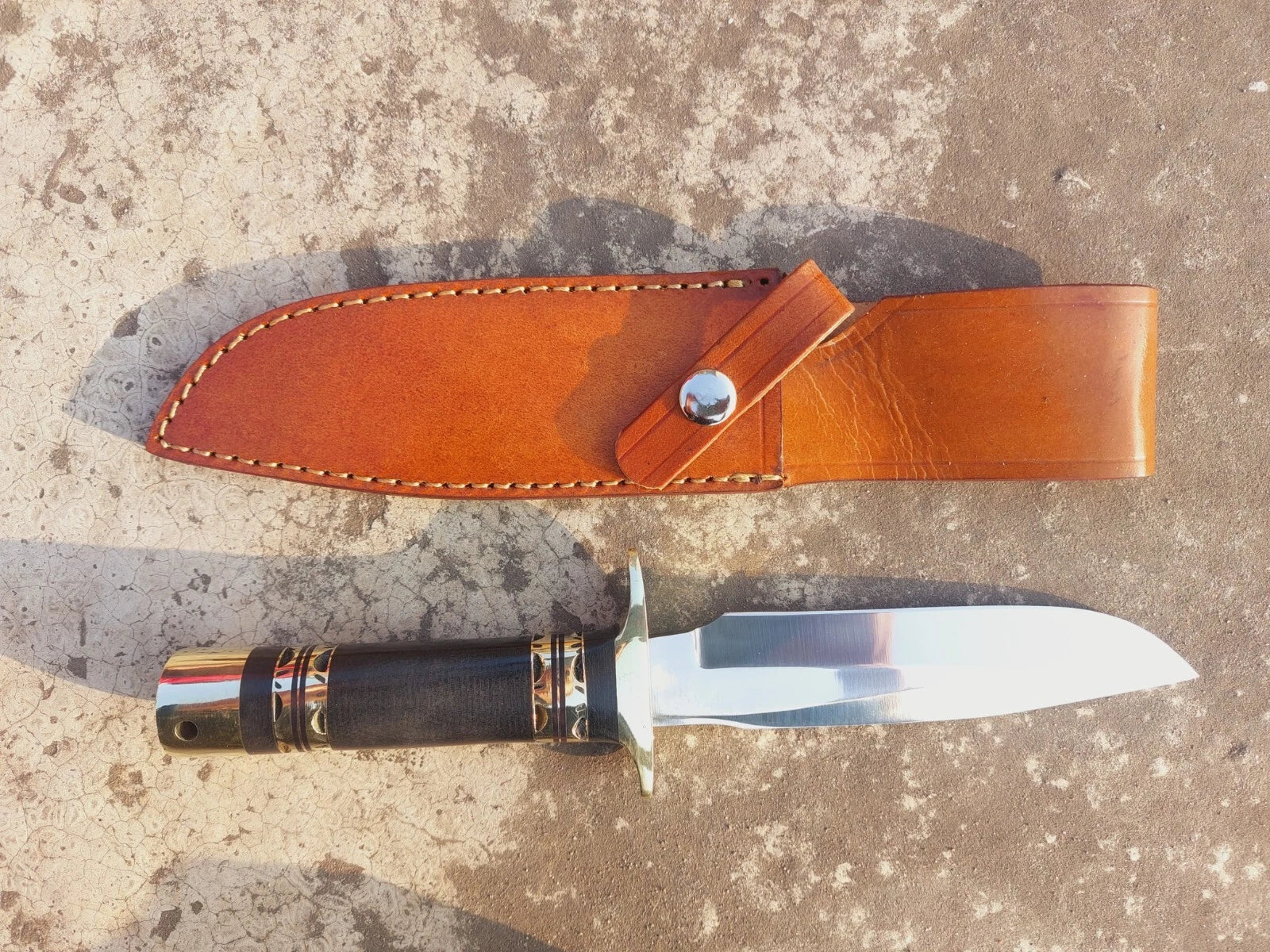 Custom outdoor knife with polished blade, micarta handle, and brass guard. Built for durability, safety, and long-term performance. Paired with a stitched leather sheath, this knife is great for hunting and outdoor adventures.