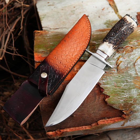 Handmade bowie knife displayed outdoors on natural wood background showing polished blade and ergonomic handle design with leather sheath. The image highlights the craftsmanship, clean blade finish, and outdoor ready appearance suitable for hunting, camping, and survival use while presenting a premium handmade look for collectors and outdoor enthusiasts.