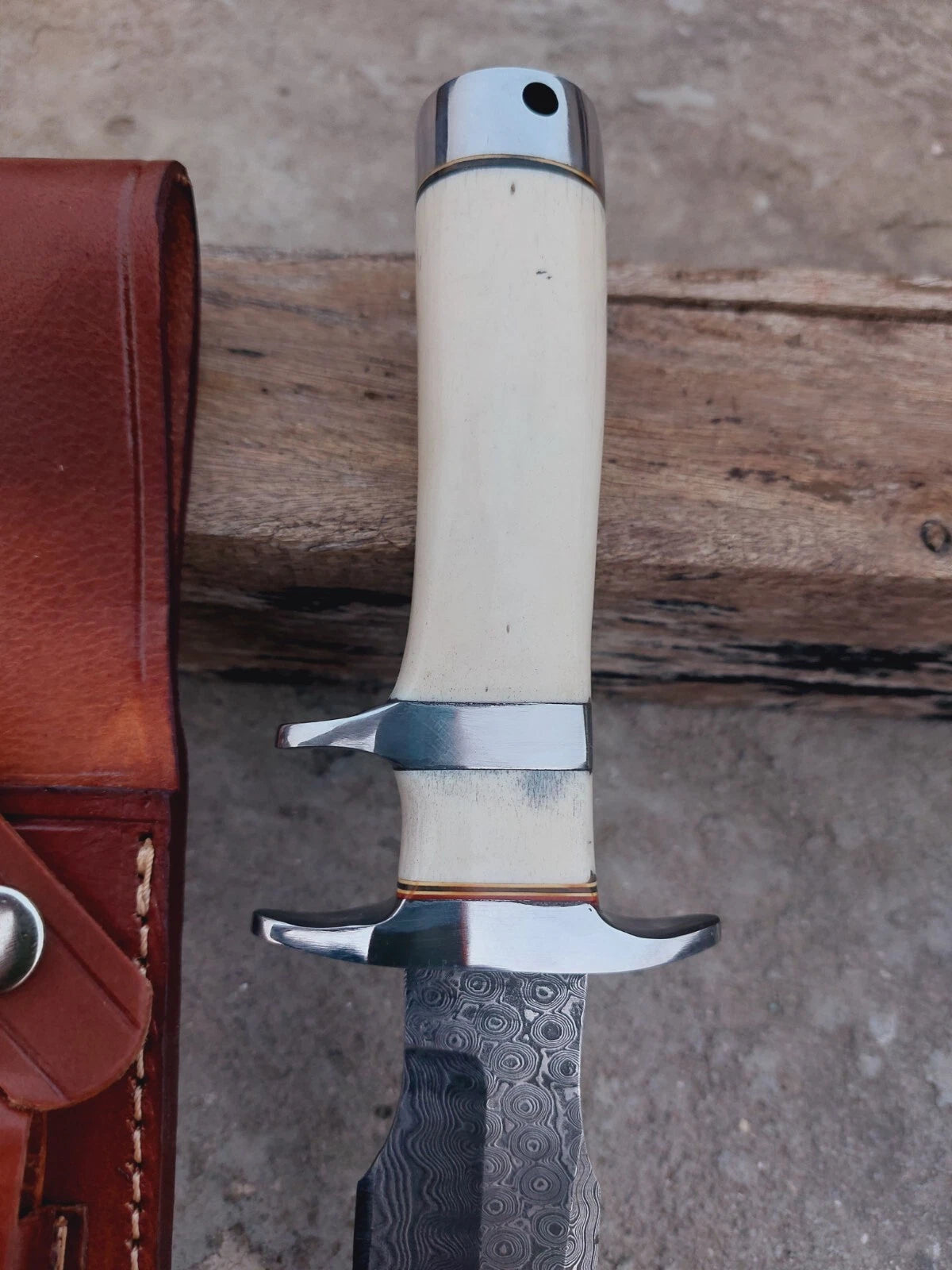 Premium handmade Damascus fixed blade knife featuring natural bone handle, detailed subhilt guard, and polished steel finish. Hand-stitched leather sheath adds protection and style. Great for hunters, campers, and collectors.