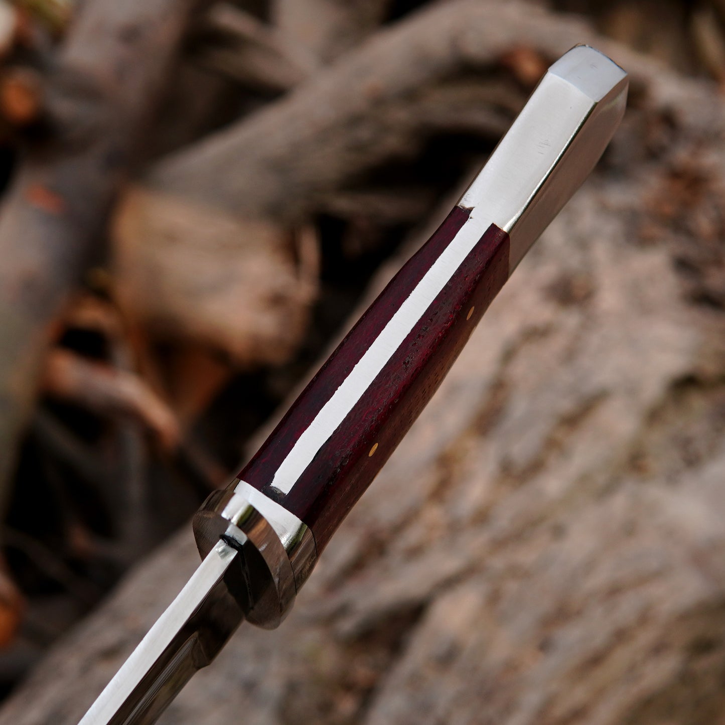 Artisan made bowie knife displayed in a rustic setting highlighting balance and design.