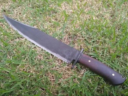 Side view of carbon steel bowie knife showing blade and rosewood handle outdoors.