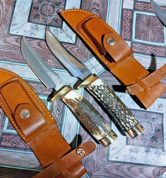 Handmade lot of 2 hunting knives featuring one damascus steel blade and one carbon steel blade, both with stag antler handles. Supplied with leather sheathes for protection and carry, making them ideal for hunters, collectors, and outdoor enthusiasts.