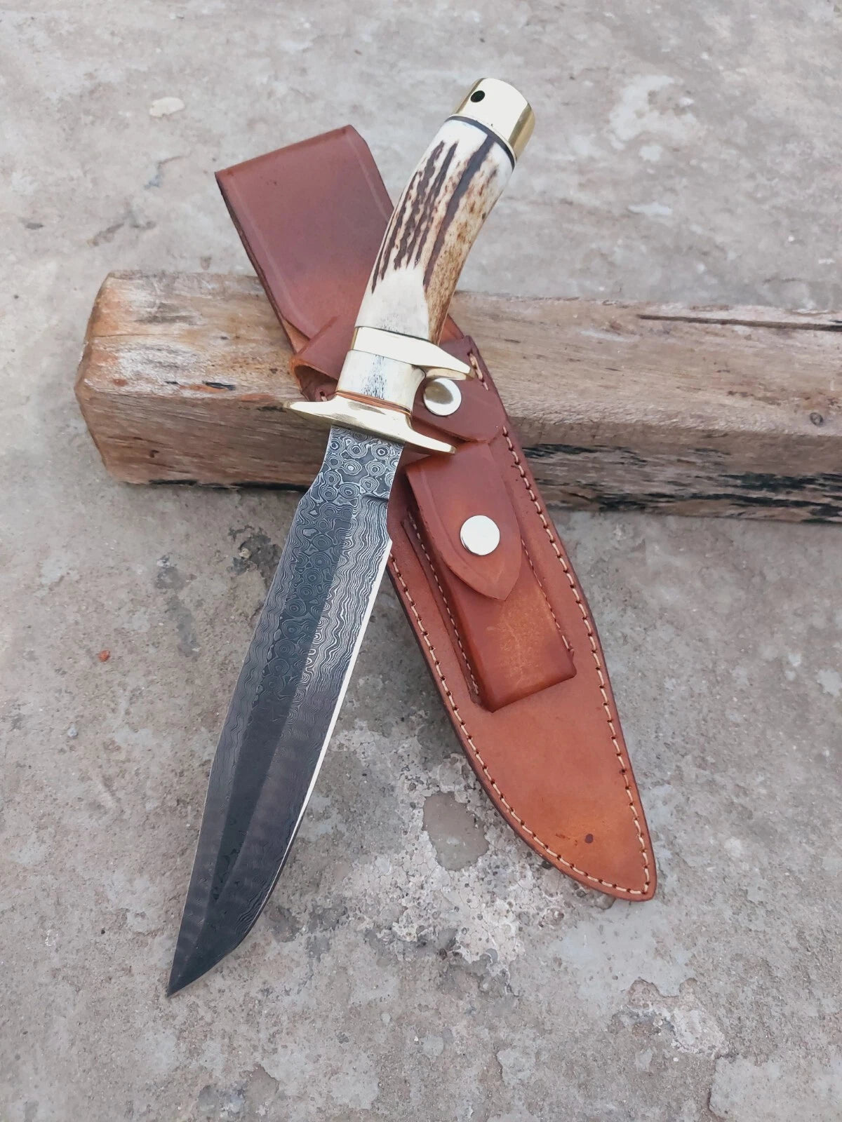 Damascus steel hunting knife forged with subhilt design and fitted with a stag antler handle. Comes with a protective leather sheath. A strong, sharp, and reliable handmade blade.