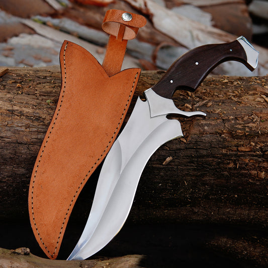 Handmade curved bowie knife displayed on natural wood background showing polished blade and ergonomic handle design. The knife is positioned in an outdoor setting highlighting craftsmanship, blade curve, and balanced structure suitable for camping, collection, or outdoor gear presentation with leather sheath included for safe carrying and storage.