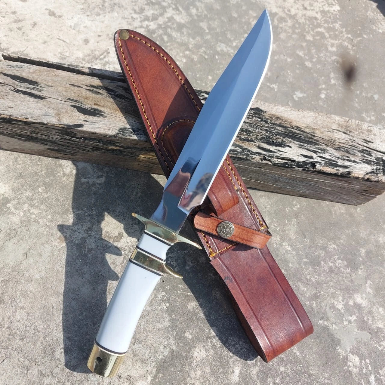 Handmade polished blade hunting knife with white handle and brass fittings. Comes with a stitched leather sheath for secure carrying. Ideal for outdoor adventures and collection display.